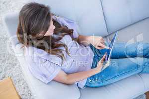 Pretty brunette using her tablet pc on couch