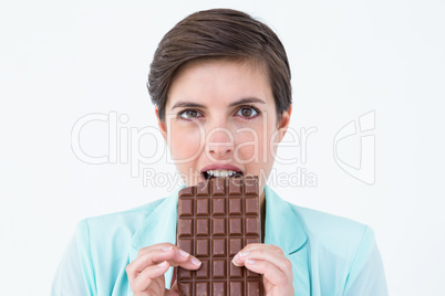 Happy brunette eating bar of chocolate
