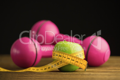 Pink dumbbells with green apple and measuring tape