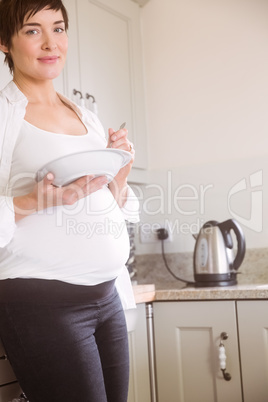 Pregnant woman having bowl of salad