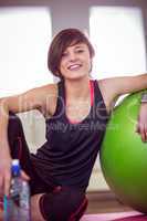 Fit woman sitting next to exercise ball
