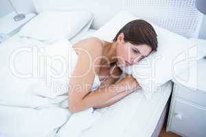 Sad woman lying in her bed