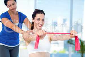 Brunette stretching with her coach and pink cloth