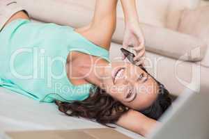 Pretty brunette lying on the floor and using her mobile phone
