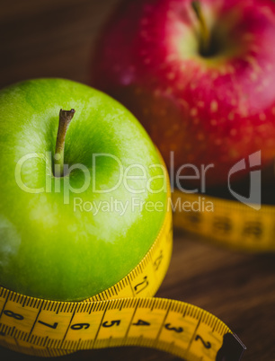 Green and red apples with measuring tape