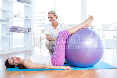 Trainer helping woman with exercise ball
