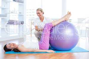 Trainer helping woman with exercise ball