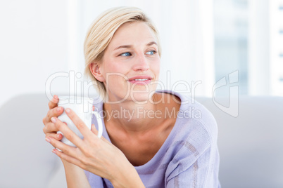 Pretty blonde woman relaxing on the couch and holding a mug