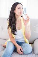 Pretty brunette drinking glass of water on couch