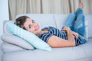 Beautiful woman lying on couch smiling at camera