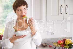 Pregnant woman having bowl of salad