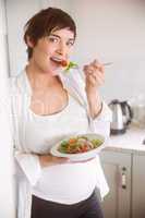 Pregnant woman having bowl of salad