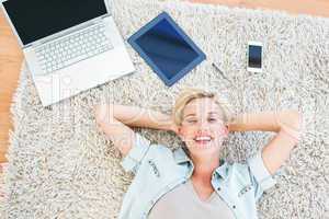 Pretty blonde woman lying on the floor and smiling at the camera