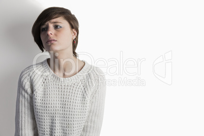 Sad pretty brunette leaning against wall