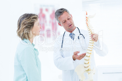 Doctor having conversation with his patient and showing spine mo