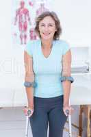 Woman standing with crutch and smiling at camera