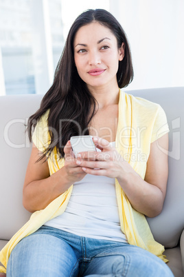 Pretty brunette using smartphone in the living-room