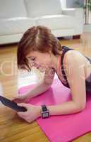 Fit woman using tablet pc on mat