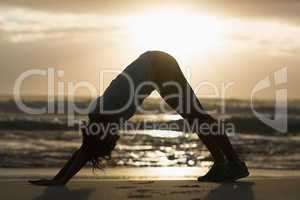 Sporty brunette stretching on the beach