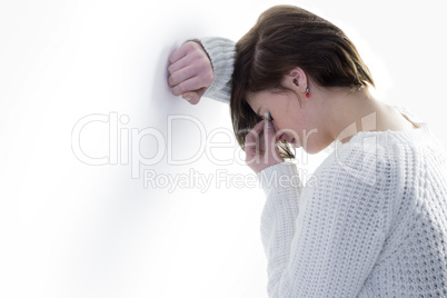 Sad pretty brunette leaning against wall