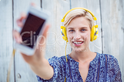 Pretty blonde woman listening music with her mobile phone