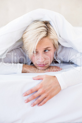 Sad blonde woman lying on the bed