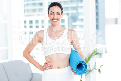 Smiling brunette holding exercise mat