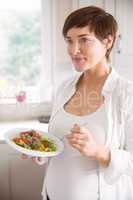 Pregnant woman having bowl of salad