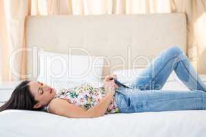 Pretty brunette trying to fit in jeans on bed