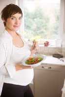 Pregnant woman having bowl of salad