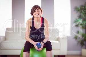 Fit woman with bottle on exercise ball