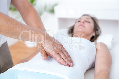 Physiotherapist examining his patients stomach