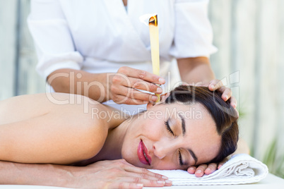 Relaxed brunette getting an ear candling treatment