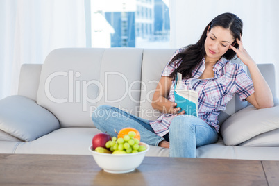 Pretty brunette reading a book in the living-room