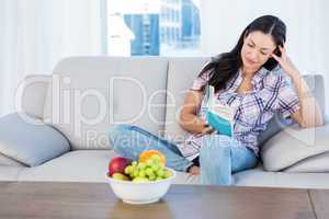 Pretty brunette reading a book in the living-room