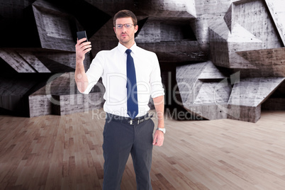 Composite image of serious businessman holding his phone Composite image of serious businessman holding his phone