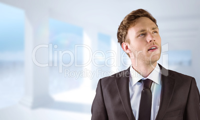 Composite image of young businessman thinking and looking up