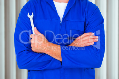 Composite image of male mechanic holding spanner on white backgr