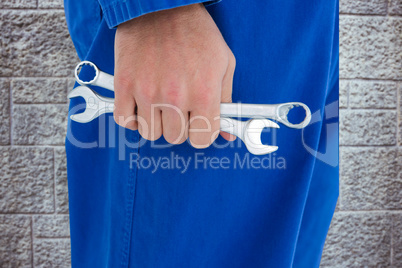 Composite image of male mechanic holding spanners