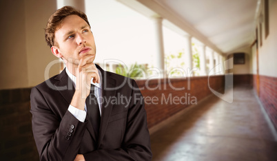 Composite image of young businessman thinking with hand on chin