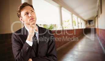 Composite image of young businessman thinking with hand on chin