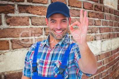 Composite image of portrait of smiling repairman gesturing okay