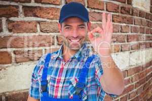 Composite image of portrait of smiling repairman gesturing okay