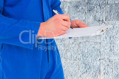 Composite image of male mechanic writing on clipboard Composite image of male mechanic writing on clipboard