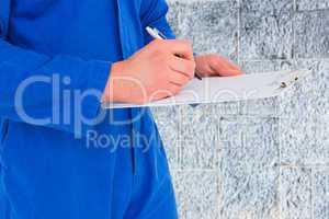 Composite image of male mechanic writing on clipboard