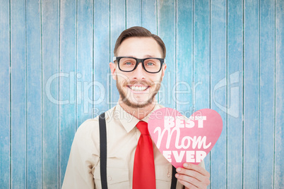 Composite image of geeky hipster smiling and holding heart card