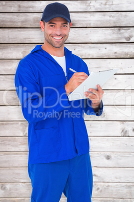 Composite image of portrait of happy male mechanic writing on cl