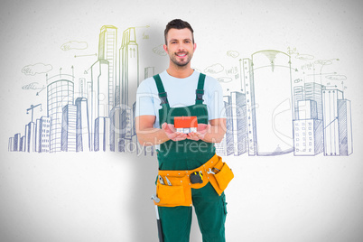 Composite image of happy construction worker holding house model