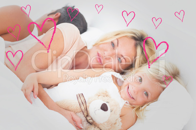 Composite image of family lying together on a bed