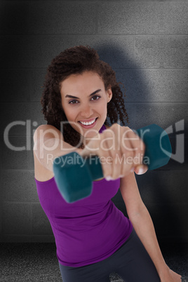 Composite image of fit woman lifting blue dumbbell